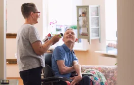 Therapeutische Betreuung - Mann in Rollstuhl mit Pflegerin